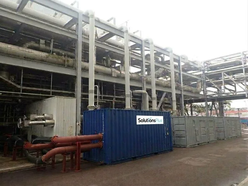 Containerised chiller and generator units beside an industrial plant with a SolutionsPlus logo