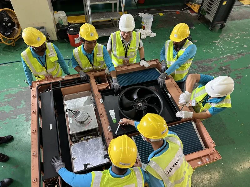 Solutions Plus engineers in hard hats and high-visibility vests servicing an air handling unit