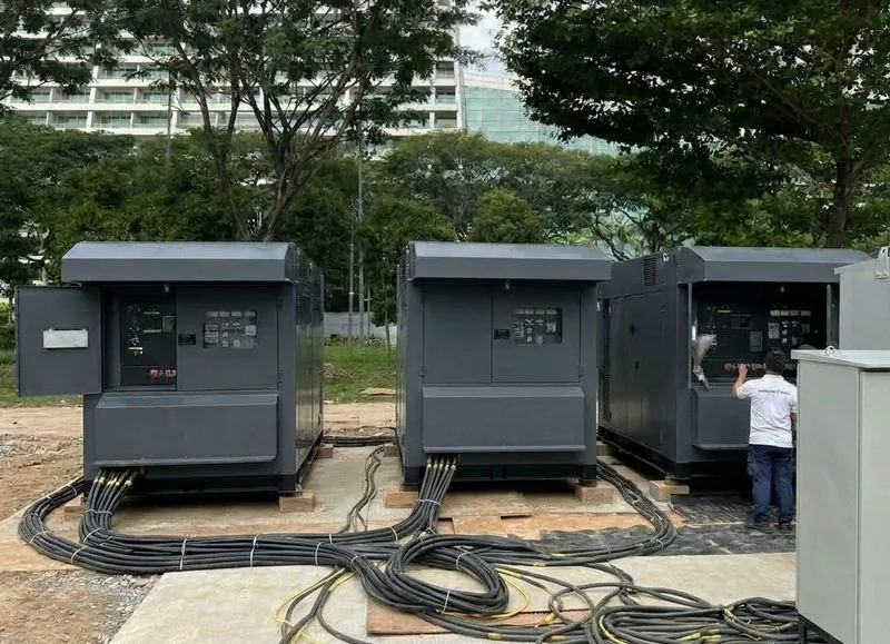 Three silenced diesel generators with power cables on a rental site